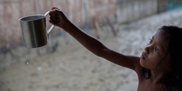 SHYAMNAGAR, SATKHIRA, KHULNA, BANGLADESH - 2015/08/28: Rani is 9 years old girl, collects rain water for drinking. Rainwater