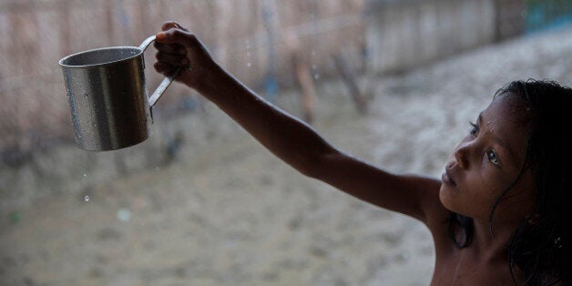 SHYAMNAGAR, SATKHIRA, KHULNA, BANGLADESH - 2015/08/28: Rani is 9 years old girl, collects rain water for drinking. Rainwater is the main source of drinking water of the Shyamnagar villagers. Ironically, there is water everywhere; they only tend to be saline. Bangladesh is one of the countries most vulnerable to the effects of climate change. The regular and severe natural hazards that Bangladesh already suffers from tropical cyclones, river erosion, flood, landslides and drought are all set to increase in intensity and frequency as a result of climate change. Sea level rise will increasingly inundate coastal land in Bangladesh and dramatic coastal and river erosion will destroy lands and homes. These and the many other adverse effects of climate change will severely impact the economy and development of the country.One of the most dramatic impacts will be the forced movement of people throughout Bangladesh as a result of losing their homes, lands, property and livelihoods to the effects of climate change. While it is impossible to predict completely accurate figures of how many people will be displaced by climate change, the best current estimates state that sea level rise alone will displace 18 million Bangladeshis within the next 40 years. The vast majority of these people will be displaced within Bangladesh not across international borders presenting the Government with enormous challenges, particularly when it comes to finding places to live and work for those displaced. (Photo by Probal Rashid/LightRocket via Getty Images)