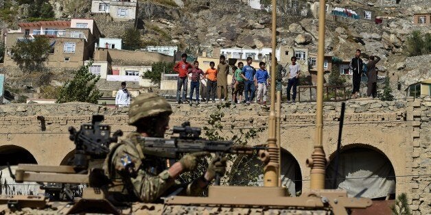 A NATO soldier keeps watch as Afghan boys stand on the rooftop of a house at the scene of a suicide car bomb attack that targeted foreign military vehicles at Jo-e-Sher in Kabul on October 11, 2015. A Taliban suicide bomber targeted a NATO convoy in downtown Kabul on October 11, triggering a powerful explosion in a rush-hour attack that comes just days after the resurgent militant group overran a key northern city.No casualties were immediately reported from the bombing, which sent a thick plume of smoke rising into the sky, as the Taliban ramp up attacks on government and foreign targets. AFP PHOTO / Wakil Kohsar (Photo credit should read WAKIL KOHSAR/AFP/Getty Images)