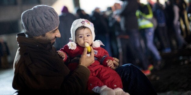 A man from Syria feeds his daughter as asylum seekers line up in front of the State Office of Health and Social Affairs (LAGe