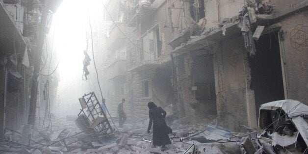 A Syrian woman makes her way through debris following an air strike by government forces in the northern city of Aleppo on Ju