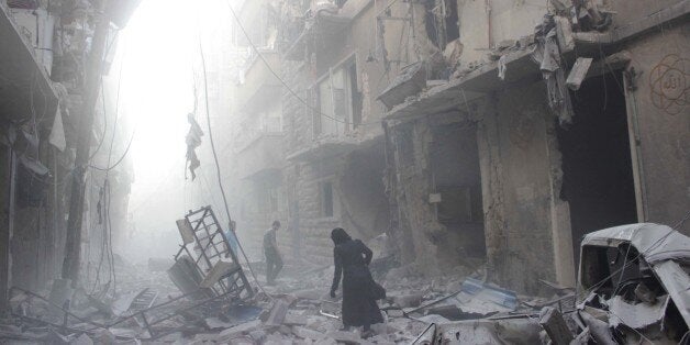 A Syrian woman makes her way through debris following an air strike by government forces in the northern city of Aleppo on July 15, 2014. More than 170,000 people have been killed in the three-year war, one third of them civilians, according to the Syrian Observatory for Human Rights. AFP PHOTO / KARAM AL-MASRI (Photo credit should read KARAM AL-MASRI/AFP/Getty Images)