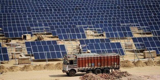 TO GO WITH: Climate-warming-COP21-India-energy-solar, FOCUS by Annie Banerji In this photograph taken on August 23, 2015, an Indian engineer positions solar panels at the under construction Roha Dyechem solar plant at Bhadla some 225 kms north of Jodhpur in the western Indian state of Rajasthan. Under a blistering sun, workers install a sea of solar panels in a north Indian desert as part of the government's clean energy push --- and its trump card at upcoming climate change talks in Paris. AFP PHOTO / MONEY SHARMA (Photo credit should read MONEY SHARMA/AFP/Getty Images)