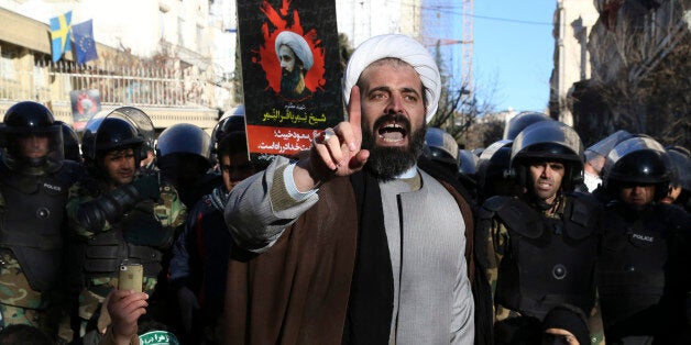 Surrounded by policemen, a Muslim cleric addresses a crowd during a demonstration to protest the execution of Saudi Shiite Sheikh Nimr al-Nimr, shown in the poster in background, in front of the Saudi embassy in Tehran, Iran, Sunday, Jan. 3, 2016. Saudi Arabia announced the execution of al-Nimr on Saturday along with 46 others. Al-Nimr was a central figure in protests by Saudi Arabia's Shiite minority until his arrest in 2012, and his execution drew condemnation from Shiites across the region. (AP Photo/Vahid Salemi)