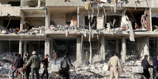 GHOUTA, SYRIA - JANUARY 6: Syrian people are seen in front of a damaged building after Assad regime forces carried out airstrike at Zamalka district in Eastern Ghouta, Syria on January 6, 2016. (Photo by Samir Tatin/Anadolu Agency/Getty Images)