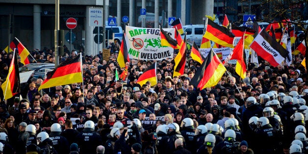 COLOGNE, GERMANY - JANUARY 09: Protesters wave German flags, alongside a banner saying 'Rapefugees Not Welcome' as supporters of Pegida, Hogesa (Hooligans against Salafists) and other right-wing populist groups protest against the New Year's Eve sex attacks on January 9, 2016 in Cologne, Germany. Over 100 women have filed charges of sexual molestation, robbery and in two cases, rape, stemming from aggressive groping and other behavior by gangs of drunken men described as Arab or North African at Hauptbahnhof on New Year's Eve. Police have recently stated that at least some of the men identified so far are refugees, which is feeding the propaganda of right-wing groups opposed to Germany's open-door refugee policy. Germany took in approximately 1.1 million migrants and refugees in 2015. (Photo by Sascha Schuermann/Getty Images)