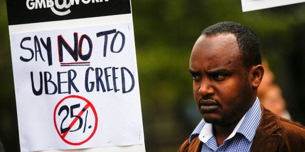 An Uber driver holds up a sign during a protest against a rise in the commission taken by Uber Technologies Inc. outside their offices in London, U.K., on Thursday, Nov. 12, 2015. Uber Technologies Inc. got a boost from a London judge who said smartphones used by its drivers arent the same as taxi meters and dont require a license from the citys transport authority. Photographer: Simon Dawson/Bloomberg via Getty Images