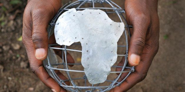 African man's hands holding tin and wire frame globe showing Africa