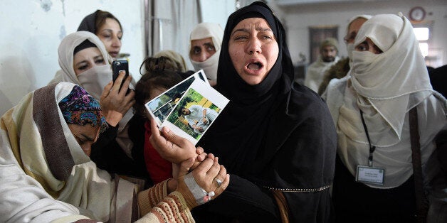 TOPSHOT - A relative of a 2014 Peshawar school attack victim shows her son's pictures to a student victim (L) of the Bacha Kh