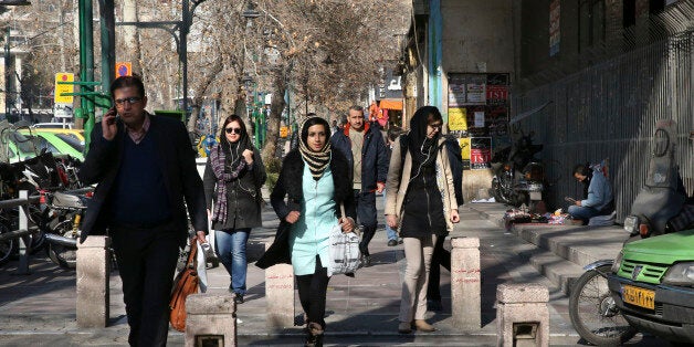 Pedestrians cross a street in central Tehran, Iran, Saturday, Jan. 16, 2016. The end of Western sanctions against Iran loomed Saturday as Iran's foreign minister suggested the U.N. atomic agency is close to certifying that his country has met all commitments under its landmark nuclear deal with six world powers. (AP Photo/Vahid Salemi)