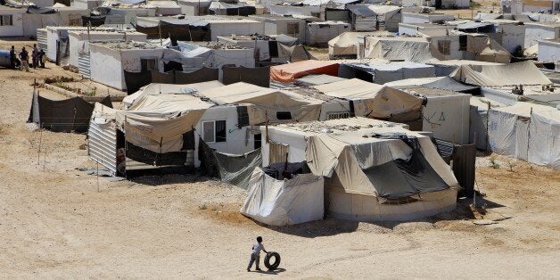 FILE- In this Wednesday, July 29, 2015 photo, a Syrian refugee boy plays with a tire at Zaatari refugee camp, in Mafraq, Jordan. The United Arab Emirates on Wednesday, Sept. 9, 2015 defended its response to the Syrian refugee crisis in the face of criticism that the country and other oil-rich Gulf states should be doing more to address the issue. (AP Photo/Raad Adayleh, File)