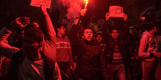 An Egyptian youth holds a lit flare as supporters of the ousted Islamist President Mohamed Morsi chant anti-government slogans, in the Faysal district of Cairo, Egypt, Monday, Jan. 25, 2016. The Muslim Brotherhood is the only group who have called on its supporters to take to the streets this Monday, the anniversary of the 2011 uprising that ousted autocrat Hosni Mubarak. Poster reads, "Down with military rule." (AP Photo/Belal Darder)