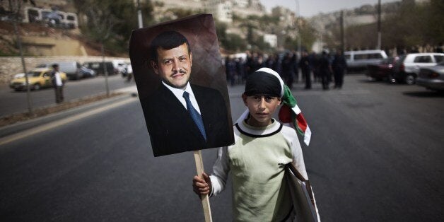 A young Jordanian parades with a portrait of the King Abdullah II in front of policemen during a pro government demonstration