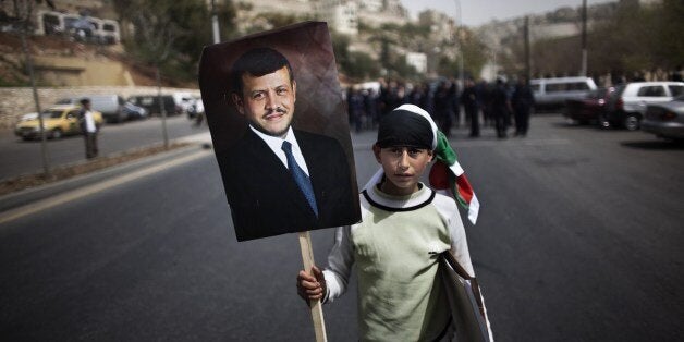 A young Jordanian parades with a portrait of the King Abdullah II in front of policemen during a pro government demonstration in Amman on April 1, 2011, as they called for reforms, a week after clashes between them and government supporters killed a man and injured 160. AFP PHOTO / MARCO LONGARI (Photo credit should read MARCO LONGARI/AFP/Getty Images)