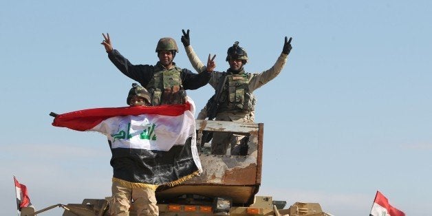 Iraqi soldiers wave their national flag after a live-fire exercise under the surveillance of US-led coalition forces at Basma
