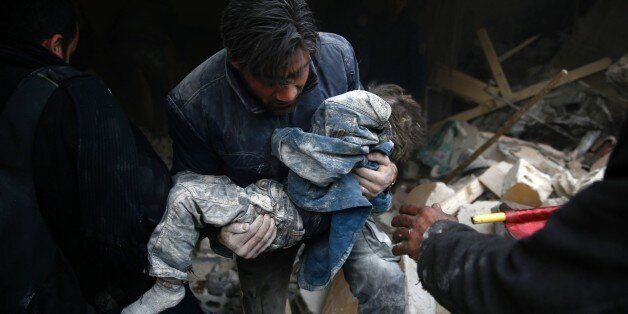 TOPSHOT - A Syrian man evacuates a child from the rubble of a destroyed building following air strikes on the Eastern Ghouta town of Douma, a rebel stronghold east of the capital Damascus, on January 10, 2016. / AFP / SAMEER AL-DOUMY (Photo credit should read SAMEER AL-DOUMY/AFP/Getty Images)