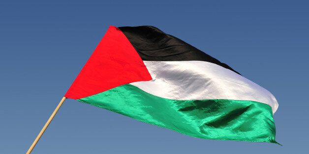 The Palestinian state flag waves in the wind with blue sky background.