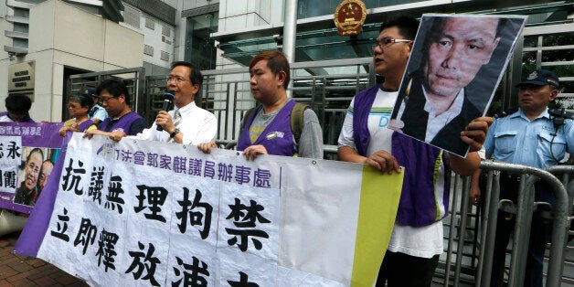 Anti-Beijing protesters, holding pictures of human rights lawyer Pu Zhiqiang, protest outside the Chinese liaison office to demand Pu's release, in Hong Kong Wednesday, May 14, 2014. Chinese police broke up a dinner party attended by activists in the eastern city of Hangzhou Tuesday night and detained a dozen people, according to an activist who attended the dinner. In recent weeks, police also detained well-known human rights lawyer Pu Zhiqiang, journalist Gao Yu and others ahead of the politically sensitive 25th anniversary of the June 4 Tiananmen Square protests and crackdown. The banner reads "Protest against unreasonable detention, release Pu Zhiqiang immediately." (AP Photo/Kin Cheung)