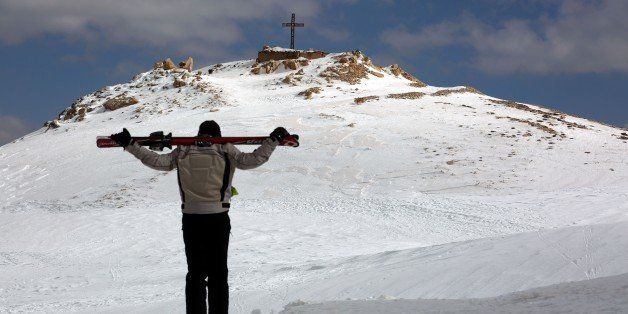 A skier holds his skis as he walks towards a hill decorated with a cross in Ouyoun al-Siman ski slopes in the Lebanese mountains on February 5, 2016. / AFP / Patrick BAZ (Photo credit should read PATRICK BAZ/AFP/Getty Images)