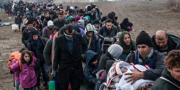 TOPSHOT - Migrants and refugees wait for security check after crossing the Macedonian border into Serbia, near the village of