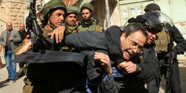 TOPSHOT - Israeli soldiers arrest an Israeli protester during clashes following a demonstration against Jewish settlements and the closing of al-Shuhada street on February 20, 2016 in the West Bank city of Hebron. Israeli troops detained ten Israelis as they joined the demonstration that was also commemorating the death of 29 Palestinian worshippers who were killed by a Jewish extremist in 1994. Some 200 people, most of them Palestinians, took part in the anniversary demonstration which was dispersed after some protesters threw stones at troops, an army spokeswoman said. / AFP / HAZEM BADER (Photo credit should read HAZEM BADER/AFP/Getty Images)