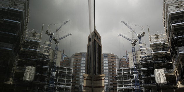 Construction cranes are reflected in the window of a neighboring building of the London Wall Place commercial property constr