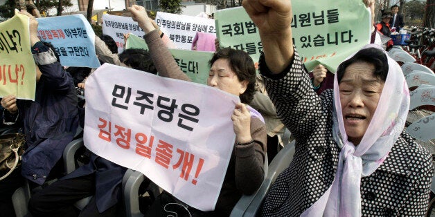 Former North Korean defectors shout a slogan during a rally demanding the improvement of North Korean's human rights near the National Assembly in Seoul, South Korea, Monday, April 4, 2011. About 100 protesters insisted the South Korean parliament to pass the law to help protect North Korean people's human rights. The letters on banners read "The main opposition Democratic Party is a henchman of North Korean leader Kim Jong Il." (AP Photo/Ahn Young-joon)