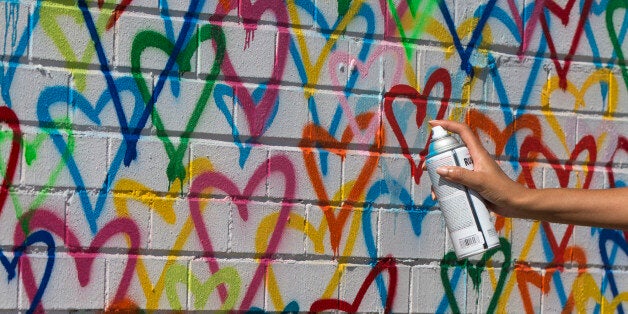 First lady Michelle Obama spray-paints Mr. Brainwash as part of a live painting of a Let Girls Learn mural at Union Market in Washington, Tuesday, March 8, 2016, in celebrations of Let Girls Learn and International Women's Day. (AP Photo/Carolyn Kaster)