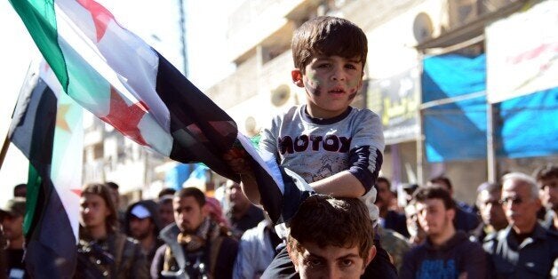ALEPPO, SYRIA - MARCH 16: A Syrian kid holds a Syrian flag during a protest against Assad Regime at Old city of Alleppo in Sy