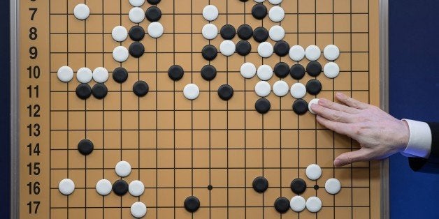 A commentator in a media room positions pieces forming a replica of a game between 'Go' player Lee Se-Dol and a Google-develo
