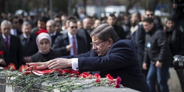 ANKARA, TURKEY - MARCH 17: Turkish Prime Minister Ahmet Davutoglu puts a Turkish flag to the place where the Ankara terror attack took place in Ankara, Turkey on March 17, 2016. (Photo by Ozge Elif Kizil/Anadolu Agency/Getty Images)