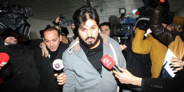 Detained Azerbaijani businessman Reza Zarrab (C) is surrounded by journalists as he arrives at a police center in Istanbul on