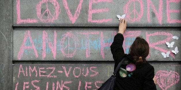 A woman sticks plastic butterfly decorations near peace messages at a makeshift memorial on the Place de la Bourse (Beursplei