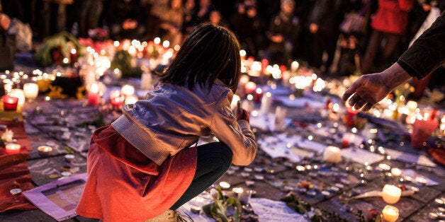 A small girl sits among candles set up at a memorial site located at the old stock exchange in Brussels on Wednesday, March 2