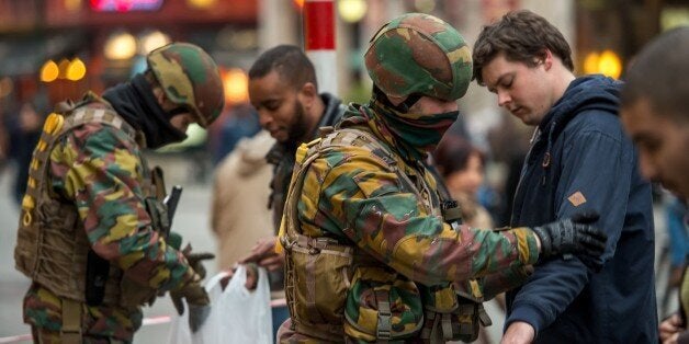 Policemen search passengers at the entrance of the De Brouckere metro station, on March 24, 2016 in Brussels, two days after