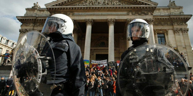 Police in riot gear protect one of the memorials to the victims of the recent Brussels attacks, as right wing demonstrators protest near the Place de la Bourse in Brussels, Sunday, March, 27, 2016. In a sign of the tensions in the Belgian capital and the way security services are stretched across the country, Belgium's interior minister appealed to residents not to march Sunday in Brussels in solidarity with the victims."We understand fully the emotions," Interior Minister Jan Jambon told reporters. "We understand that everyone wants to express these feelings."(AP Photo/Alastair Grant)