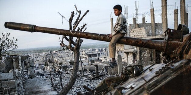 A Syrian Kurdish boy sits on a destroyed tank in the Syrian town of Kobane, also known as Ain al-Arab, on March 27, 2015. Islamic State (IS) fighters were driven out of Kobane on January 26 by Kurdish and allied forces. AFP PHOTO/YASIN AKGUL (Photo credit should read YASIN AKGUL/AFP/Getty Images)