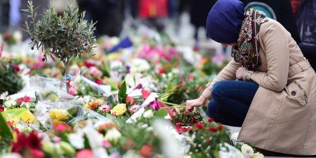 A Muslim woman lights a candle at a makeshift memorial for the victims of the terrorist attacks in France, in front of the French embassy in Berlin on November 16, 2015. AFP PHOTO / JOHN MACDOUGALL (Photo credit should read JOHN MACDOUGALL/AFP/Getty Images)