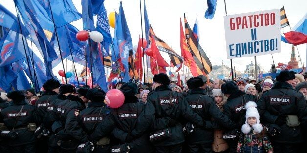 Police officers stand guard during a rally to celebrate the second anniversary of Russia's annexation of Crimea just off Red