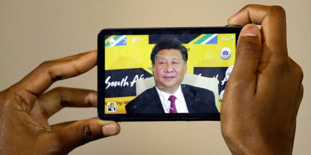A journalist takes a photo of Chinese President Xi Jinping, using a mobile phone during a joint media conference with South A