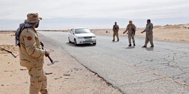 Libyan soldiers manning a military outpost, stop a car at a checkpoint in Wadi Bey, west of the city of Sirte, which is held