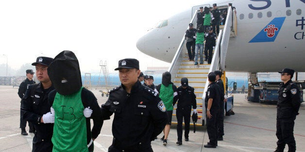 FILE - In this file photo taken April 13, 2016, and released by Xinhua News Agency, Chinese and Taiwanese suspects involved in wire fraud are escorted off a plane upon arriving at the Beijing Capital International Airport in Beijing, China. A 10-member delegation from Taiwan of judicial and police officials arrived in Beijing on Wednesday seeking to ensure fair treatment for their nationals who were deported from Kenya to face wire fraud charges in China, a case that has prompted concerns that Beijing is bringing additional diplomatic pressure on the island it considers its own territory. (Yin Gang/Xinhua News Agency via AP, File) NO SALES