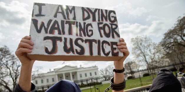 A man dressed as a detainee holds a sign calling attention to the detainees at Guantanamo Bay during a demonstration outside the White House in Washington, Friday, March 11, 2016. A coalition of activists continue to call on the Obama administration to close Guantanamo Bay detention center and end indefinite detention. (AP Photo/Andrew Harnik)