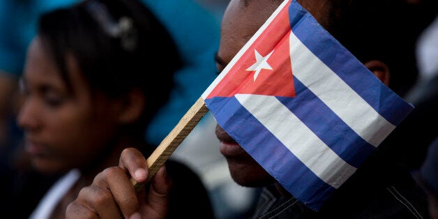 A Cuban fan uses a paper flag to shield his face from the sun during a baseball game between the Tampa Bay Rays and the Cuban national baseball team, in Havana, Cuba, Tuesday, March 22, 2016. Tampa Bay defeated the Cuban team 4-1 at a game attended by President Barack Obama and Cuba's President Raul Castro. (AP Photo/Rebecca Blackwell)