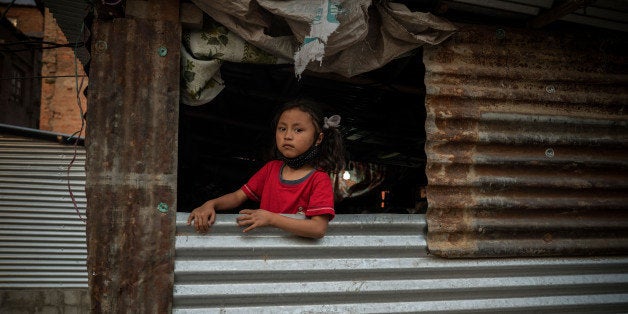 KATHMANDU, BHAKTAPUR - APRIL 24: A girl in an open window of a typical metal sheet temporary shelter in Bhaktapur on April 24, 2016 in Kathmandu, Nepal. A 7.8-magnitude earthquake struck Nepal close to midday on April 25 lasts year. It was knowned to be Nepal's worse earthquake in history as an estimated 9,000 people died and countless towns and villages across central Nepal were destroyed. Based on reports, the government promised 2,000USD to affected households but has only paid out a fraction of the amount so far and an estimated 660,000 families are still living in sub-standards temporary shelters or unsafe accommodations one year later. (Photo by Tom Van Cakenberghe/Getty Images)