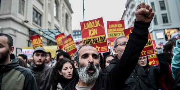 Protesters shout slogans and hold placards reading 'We will resist for secularism' on April 26, 2016 at kadikoy district in Istanbul, during a protest against a call for the country to adopt a religious constitution.Turkish police today fired tear gas to disperse demonstrators who had gathered outside parliament to protest a call for the country to adopt a religious constitution. Police broke up a group of more than 100 protesters, preventing them from making a press declaration outside the parliament in Ankara, an AFP photographer reported. / AFP / OZAN KOSE (Photo credit should read OZAN KOSE/AFP/Getty Images)