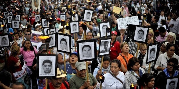 The parents of 43 missing students from Ayotzinapa teachers school hold their portraits and torches during a march 18 months after their disappearance in Mexico City on April 26, 2016. / AFP / YURI CORTEZ (Photo credit should read YURI CORTEZ/AFP/Getty Images)