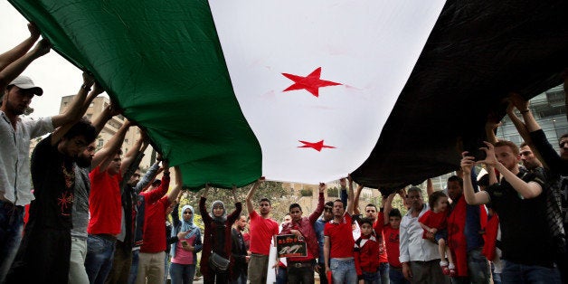 Protesters hold up a giant Syrian revolution flag during a protest in front of the United Nations Headquarters in Beirut, Lebanon, Sunday, May 1, 2016, against Syrian President Bashar Assad's military operations in areas held by insurgents around the country, mostly in the northern city of Aleppo that has been the main point of violence. (AP Photo/Bilal Hussein)