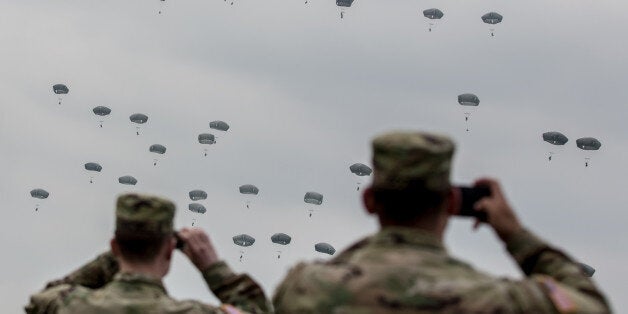 GRAFENWOEHR, GERMANY - APRIL 12: U.S. soldiers look at paratroopers from the U.S. Army 173rd Airborne Brigade, the UK's 16 Air Assault Brigade and Italian Folgore Airborne Brigade as they parachute to the ground during a training jump as part of the Saber Junction 16 military exercises near the Hohenfels Training Area on April 12, 2016 near Grafenwoehr, Germany. More than 1,200 paratroopers participated in the jump, one of the biggest airborne training operations in Europe this year. Saber Junction 16, taking place from March 31 to April 24, is the U.S. Army Europe's largest combat training in 2016 and nearly 5,000 participants from 16 NATO and European partner nations are taking part in the exercise. The U.S. military conducts training exercises with NATO-member armed forces as well as partner nations, many of them eastern European nations, on a regular basis. (Photo by Matej Divizna/Getty Images)