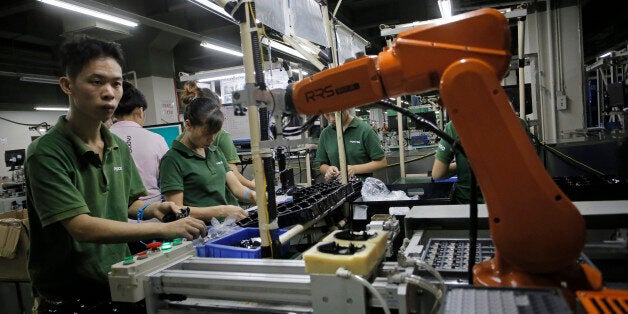 In this Aug. 21, 2015 photo, a Chinese man works amid orange robot arms at Rapoo Technology factory in southern Chinese industrial boomtown of Shenzhen. Factories in China are rapidly replacing those workers with automation, a pivot thatâs encouraged by rising wages and new official directives aimed at helping the country move away from low-cost manufacturing as the supply of young, pliant workers shrinks. (AP Photo/Vincent Yu)